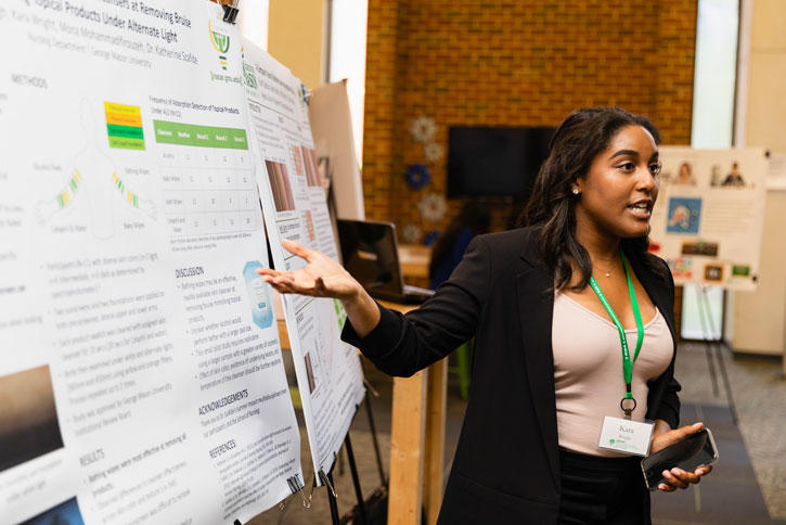 Senior Kara Wright talks about a summer research project during the OSCAR Summer Celebration in the MIX at Fenwick on Mason's Fairfax Campus. The event included 70 poster presentations by 113 students.