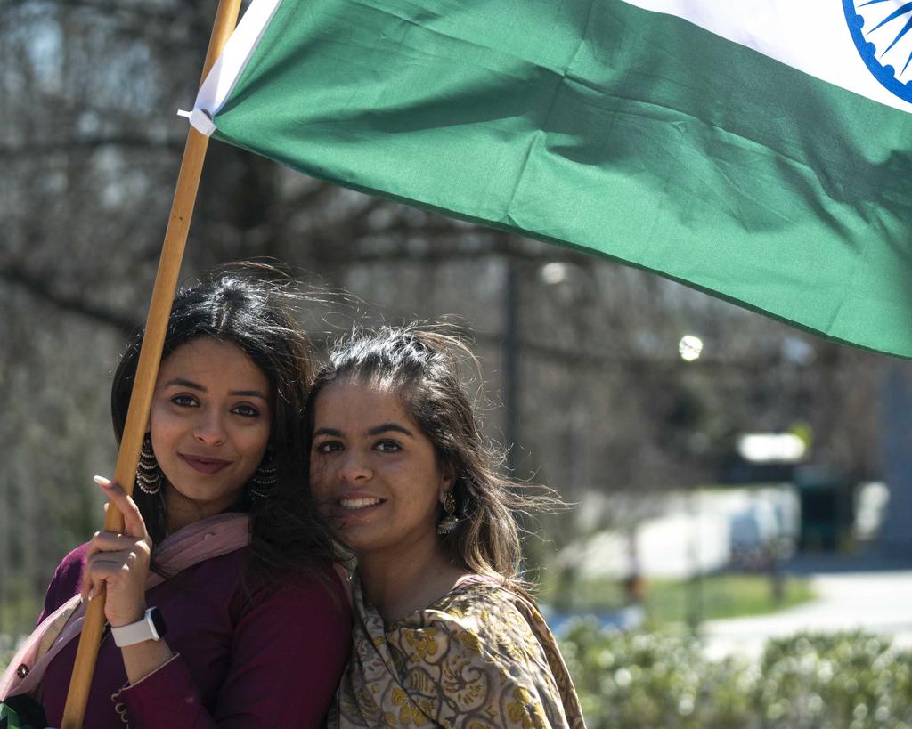 Two Mason students stand together holding the flag of their country.