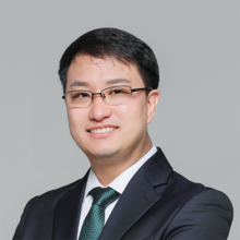 Smiling man with short dark hair and black glasses.