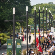 Students walking on Fairfax campus below George Mason University themed banners.