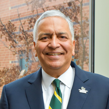 Smiling man with gray hair wearing a suit and tie