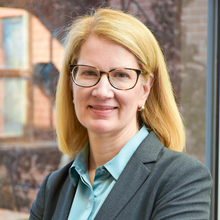 Smiling woman with long blond hair wearing dark rimmed glasses