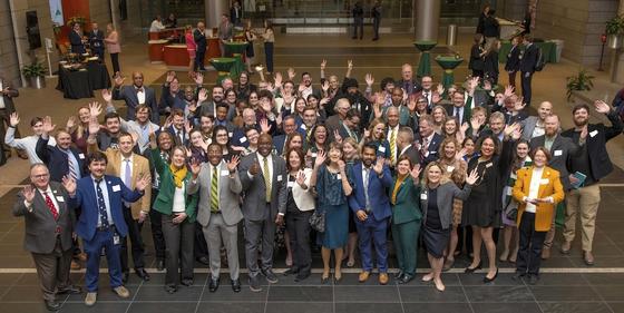 A crowd of people in business attire waving up at the camera